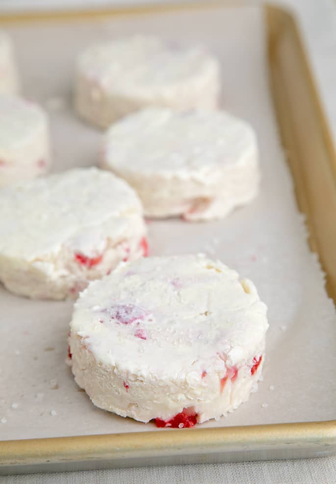 Raw cut strawberry shortcake biscuits on white paper on tray