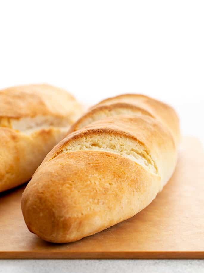 Two loaves of French bread on a light brown cutting board