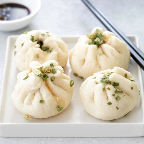 4 gluten free Chinese meat buns on white plate with chop sticks