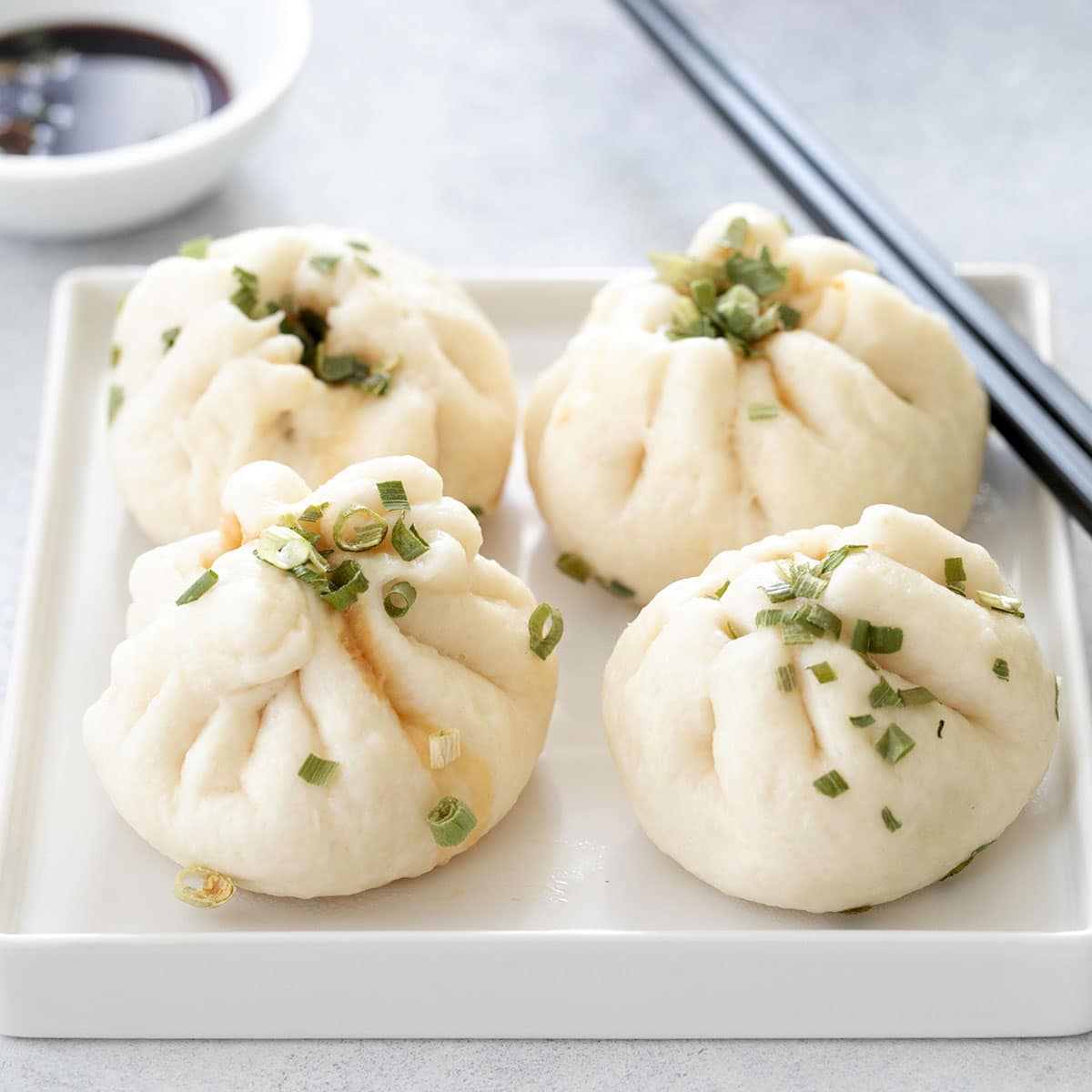 4 gluten free Chinese meat buns on white plate with chop sticks