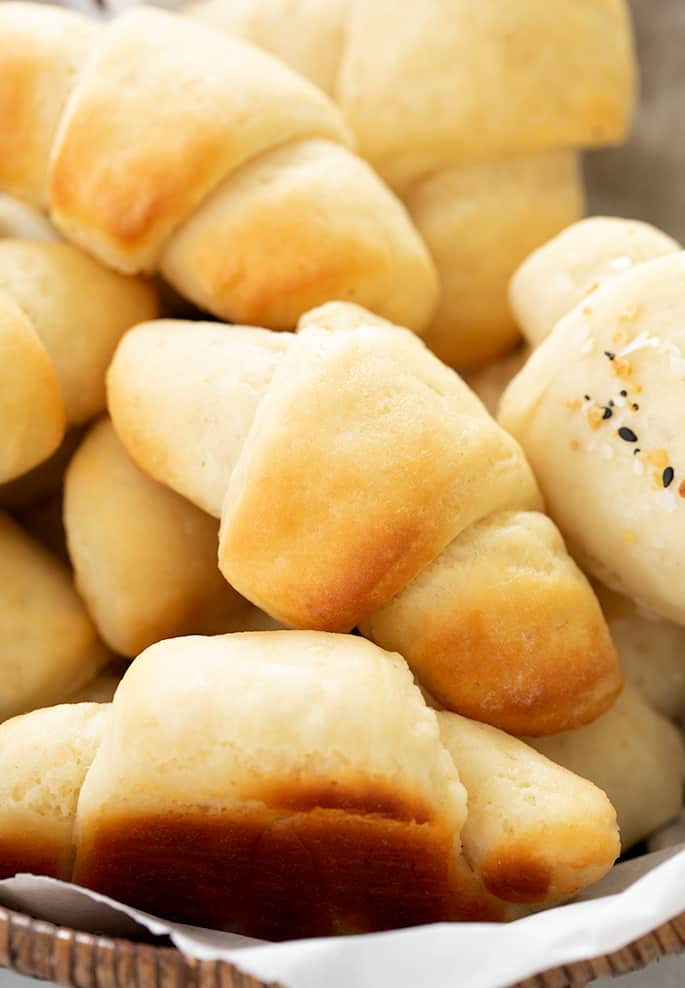 Crescent rolls in a pile on white paper in a brown basket