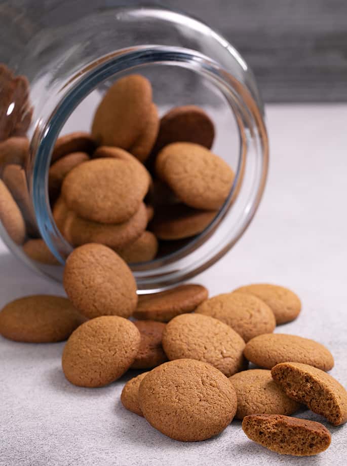 Gingersnaps poured out of glass jar onto white table