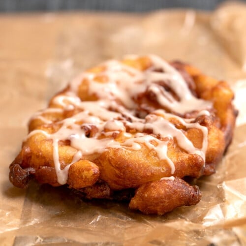 gluten free apple fritter with glaze on brown waxed paper bag