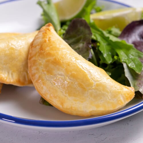 3 gluten free empanadas on white plate with greens