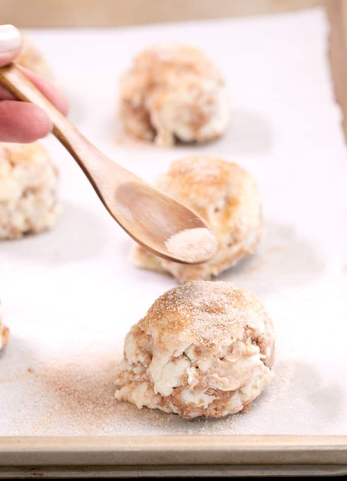 Cinnamon sugar drop biscuit raw with cinnamon sugar being sprinkled from a spoon