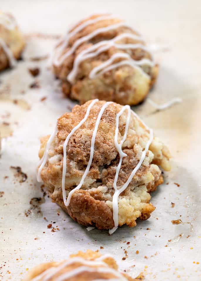 Cinnamon sugar drop biscuit with white drizzled glaze on white paper