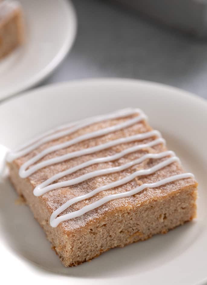 Apple snickerdoodle cookie bar with glaze drizzle on a small white plate