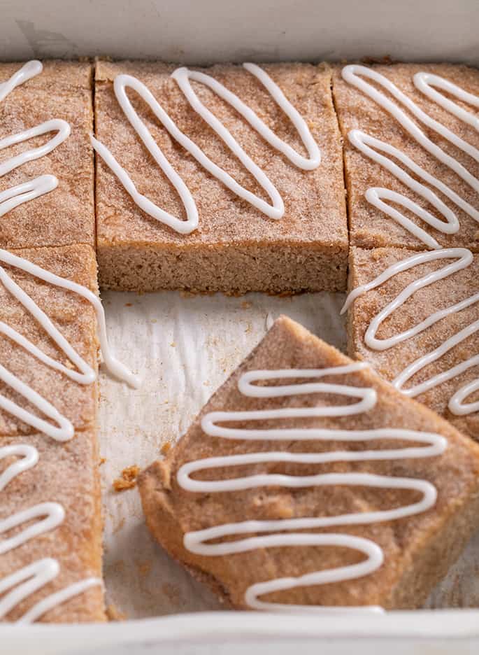 Apple snickerdoodle cookie bars cut but still in pan with glaze