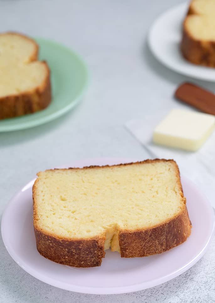 Brioche bread 3 slices each on a separate small plate with butter in background