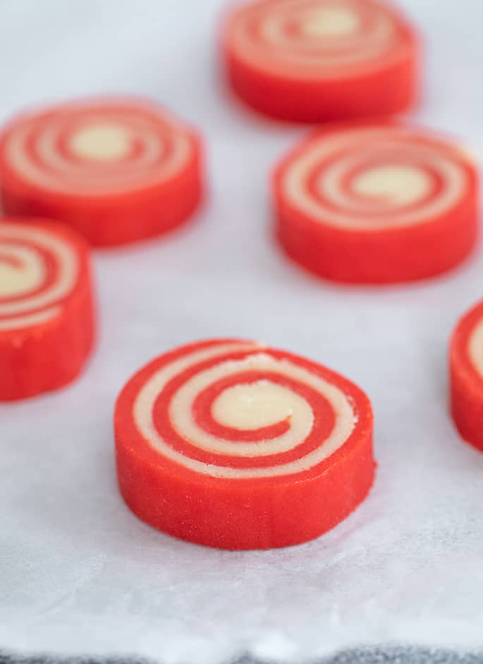 Individual raw red and white pinwheel cookies on white paper