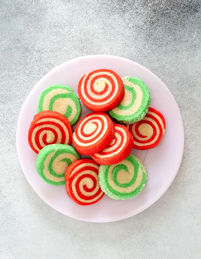 Overhead image of green and red striped pinwheel cookies on a plate