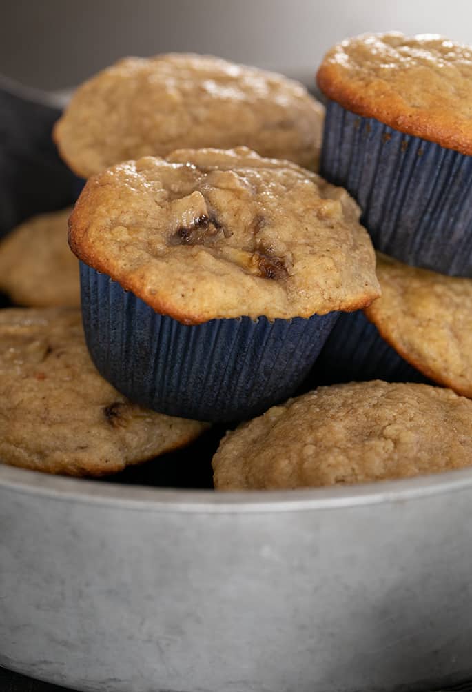 Almond flour banana muffins with banana pieces baked on top in round metal tin