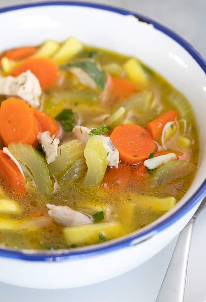 Closeup image of chicken noodle soup in white bowl with blue rim