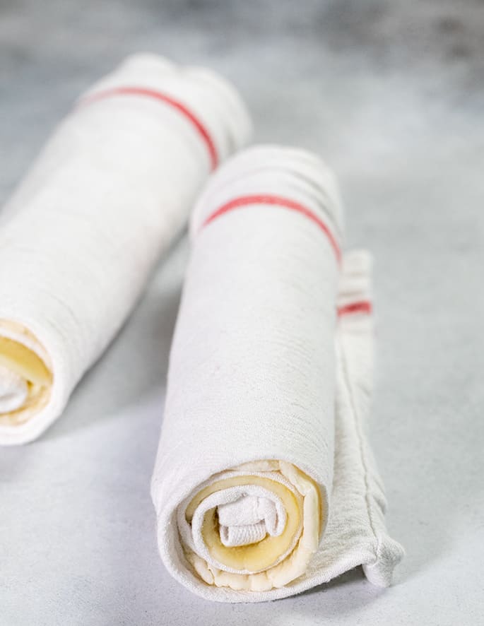 Flatbreads rolled tightly into white towels with red stripes