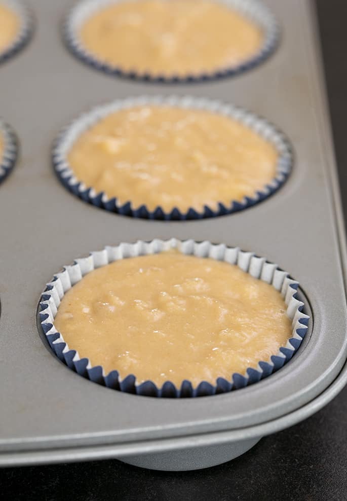 Raw banana muffin batter in blue baking cups in muffin tin wells