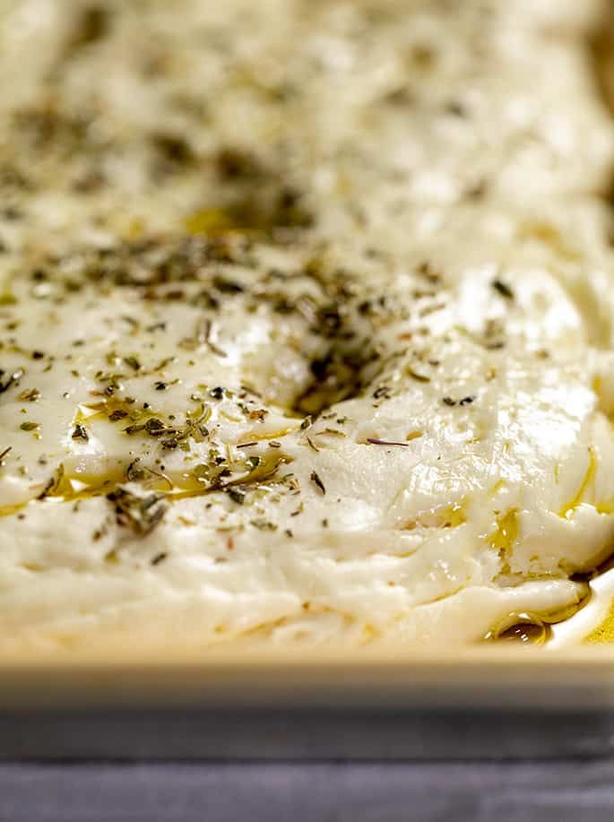 Risen and shaped raw focaccia dough in baking pan