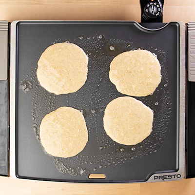 4 uncooked banana pancakes on griddle