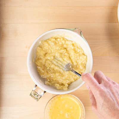 Mashing banana in bowl with fork