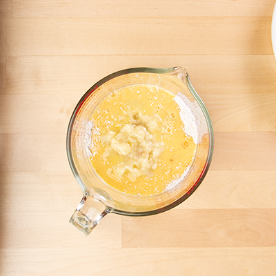 Measuring cup with mashed banana and beaten eggs