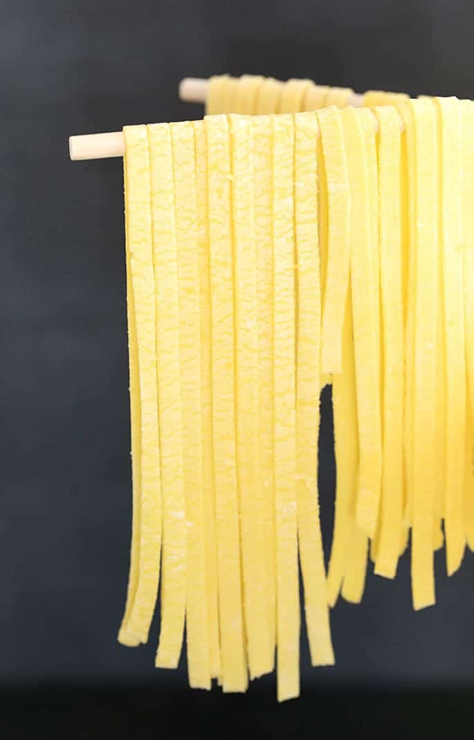 Side view of row of fettuccine egg noodles on pasta drying rack