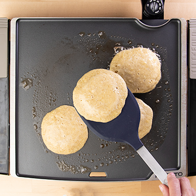 Spatula flipping banana pancakes to cook other side