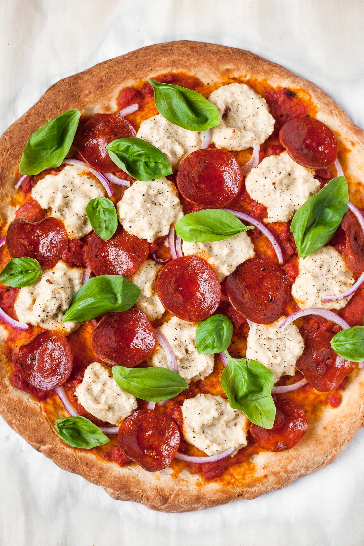 Overhead image of Paleo pizza with pepperoni, dairy free cheese, onions, and fresh basil