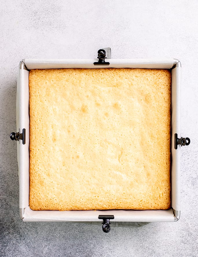 Baked lemon brownies in square pan with white paper lining