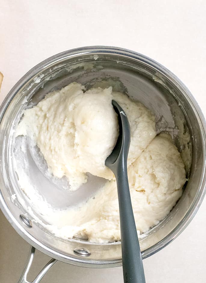 Choux pastry paste with black mixing spoon in metal saucepan