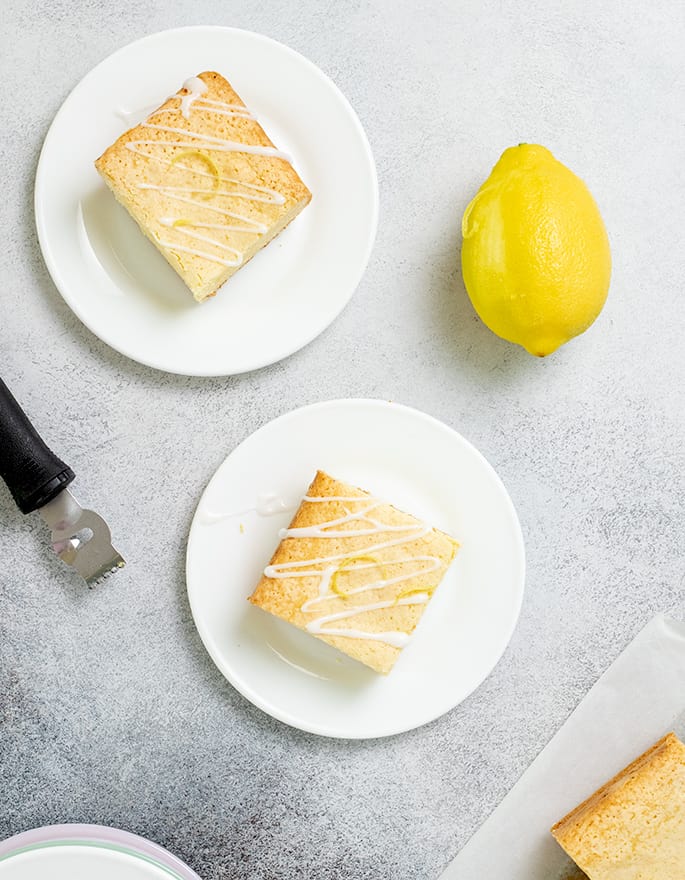 Overhead image of lemon brownies on small white plates with lemon and zester