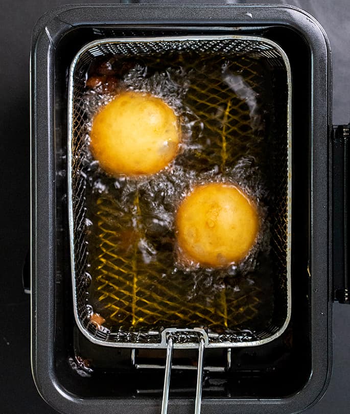 Two fried Oreos frying in a frying basket