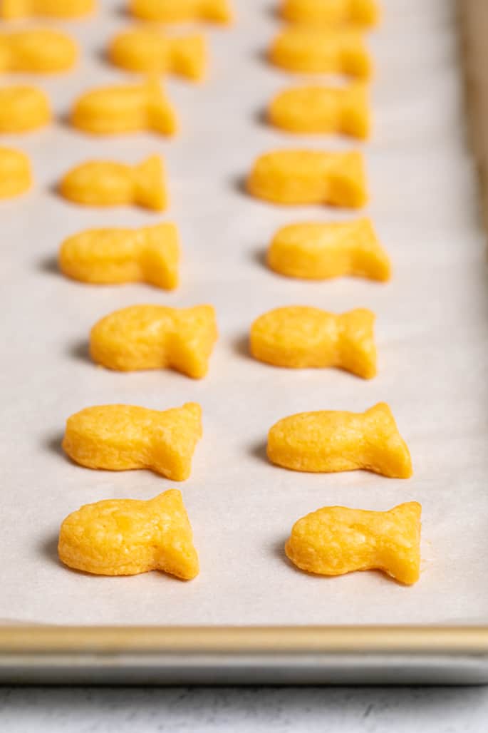 Baked goldfish-shaped crackers on white paper on tray