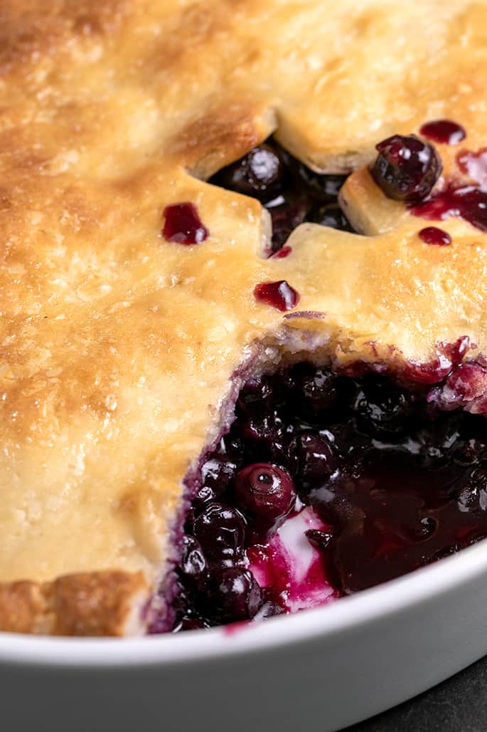 Blueberry cobbler with one serving missing showing blueberry filling underneath