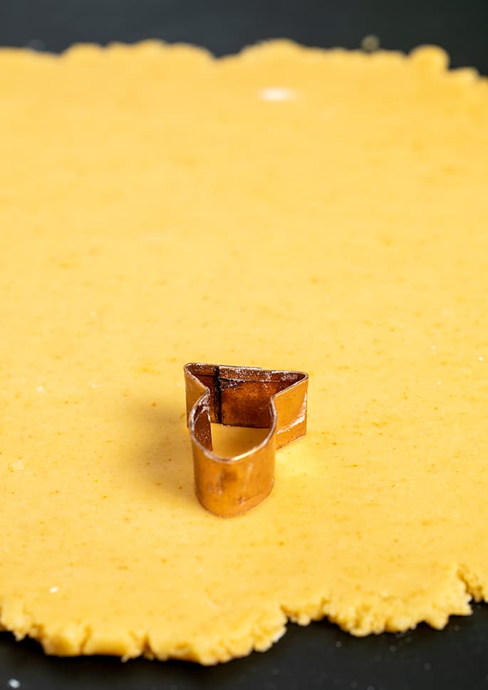 Copper goldfish shaped cookie cutter on top of light orange rolled out dough