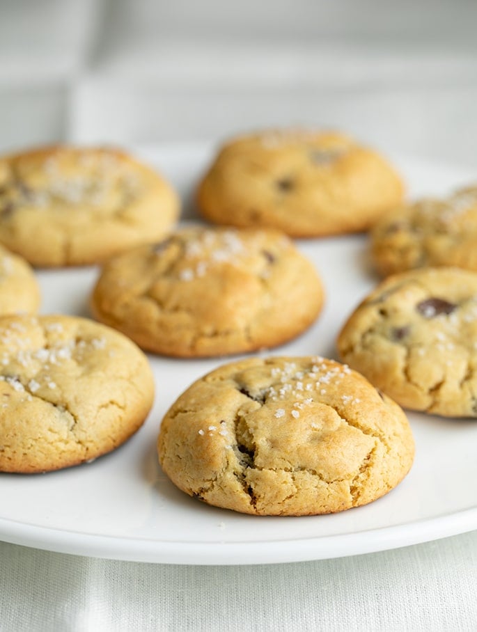 Chocolate chip cookies on flat round white platter on white cloth