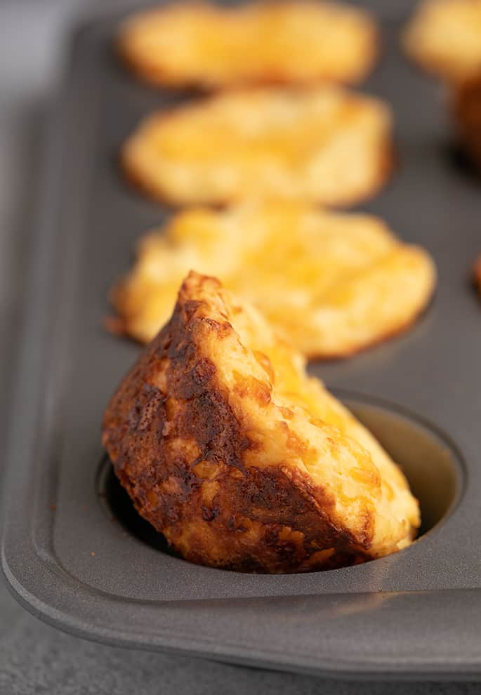 Baked muffins in tin with one in foreground on its side