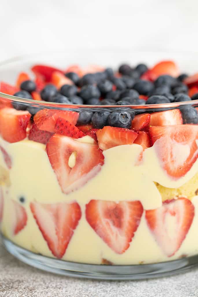 Custard, strawberries, blueberries and pound cake in round glass dish