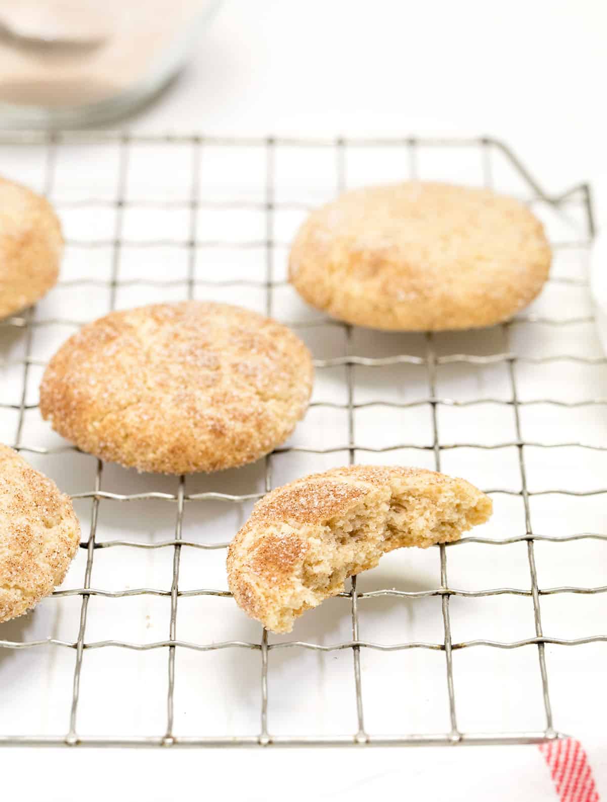 gluten free snickerdoodles cookies on wire rack with one cookie broken in half