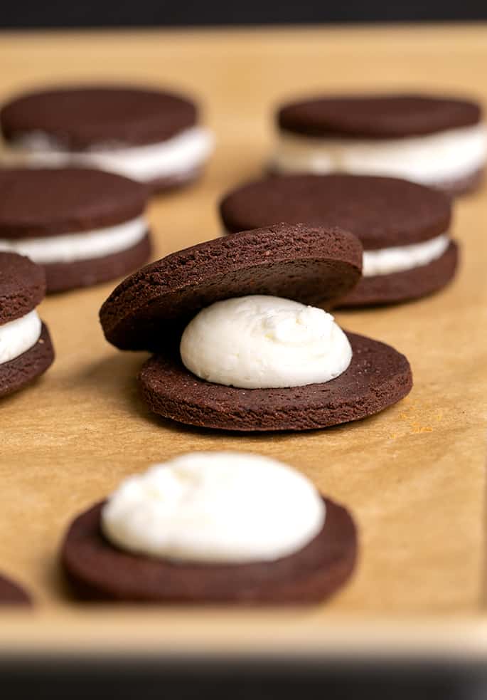 Round chocolate sandwich cookies with white filling and one with a lid partially on