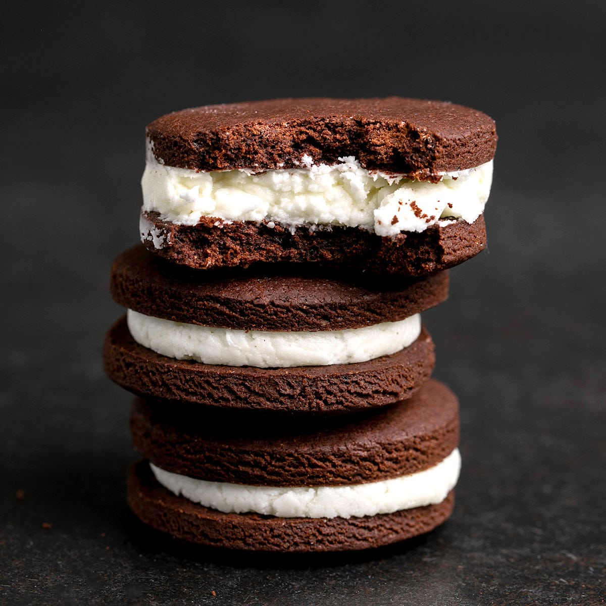 stack of 3 homemade gluten free oreos with the top one with a piece missing