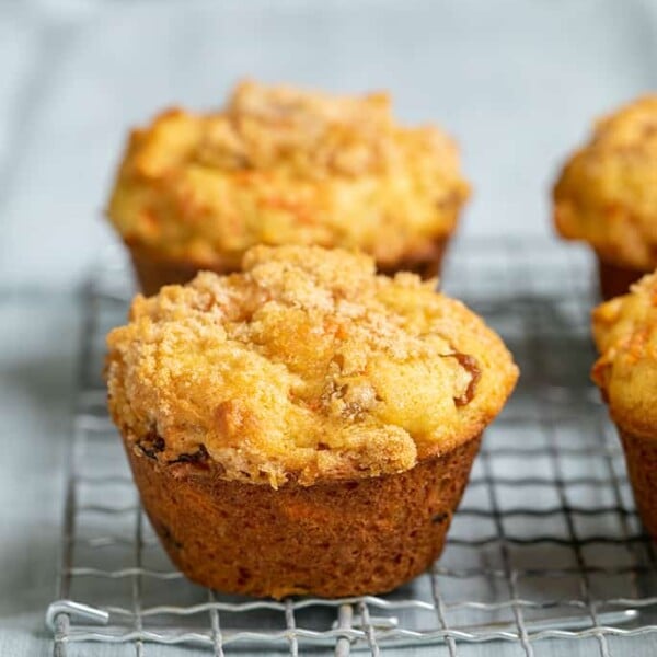 4 carrot muffins on a wire rack on a light blue cloth