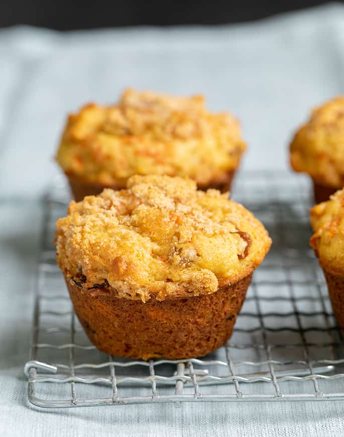 4 carrot muffins on a wire rack on a light blue cloth