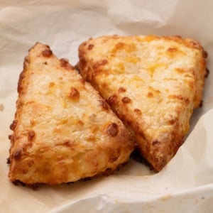 closeup of 2 triangular cheese scones on brown paper