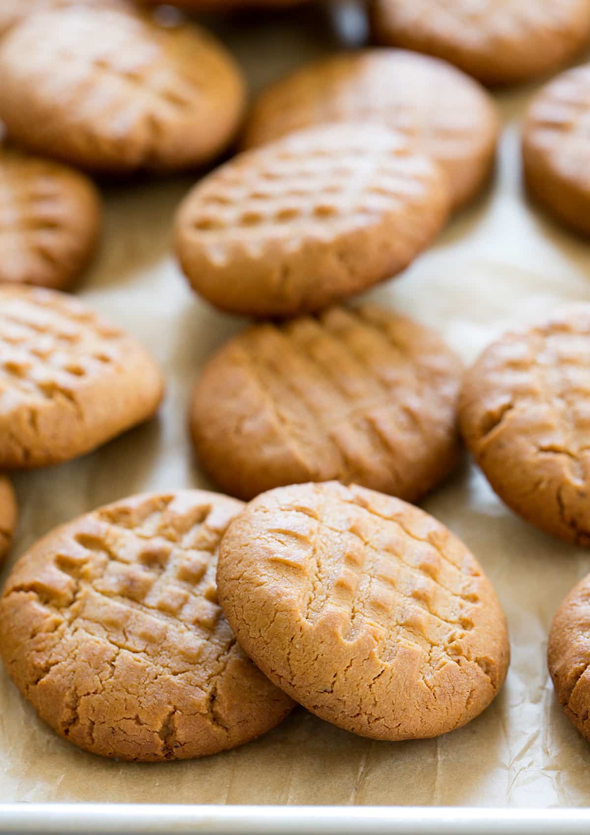 An overhead view of peanut butter cookies on beige paper