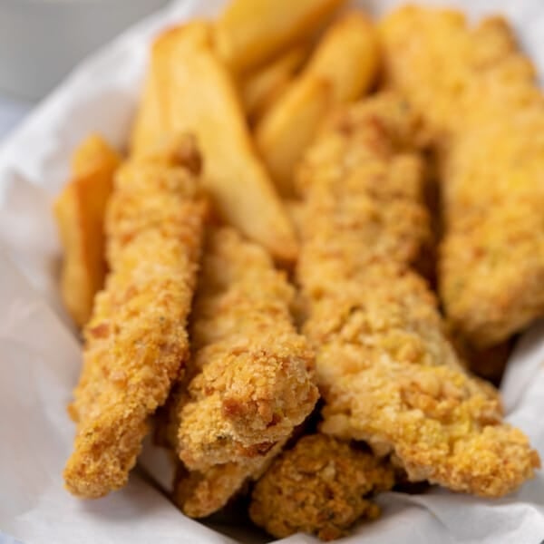 5 baked gluten free chicken tenders on white paper in plate