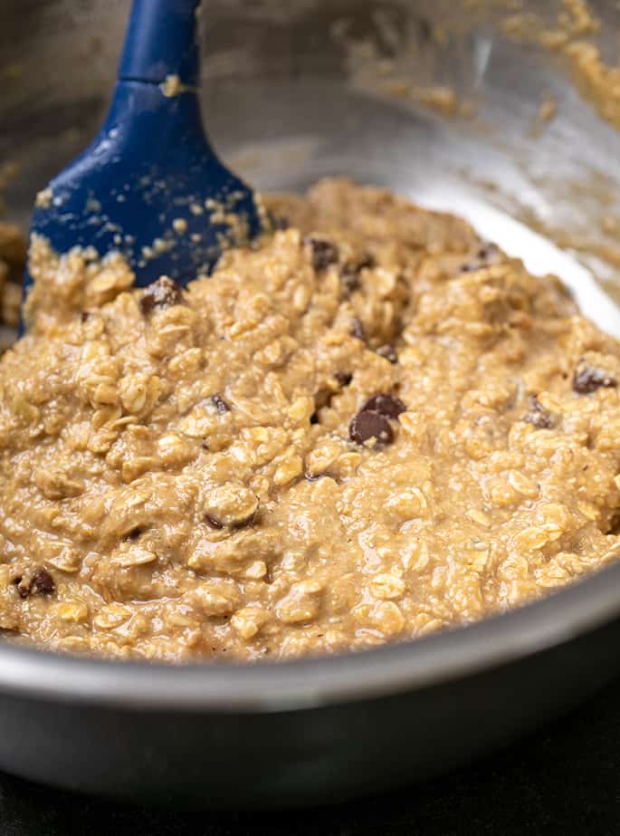 large metal mixing bowl with soft brown oatmeal cookie dough with chocolate chips