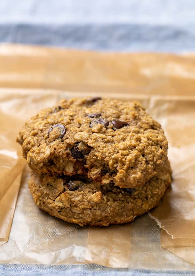 stack of 2 large brown oatmeal cookies with chocolate chips with the cookie on top missing a bite