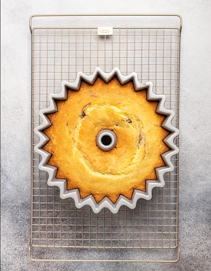 Overhead image of top of yellow cake in bundt pan on wire rack on white surface