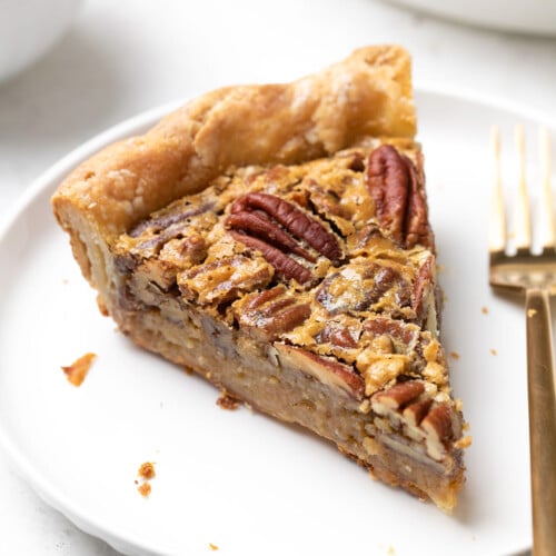 slice of gluten free pecan pie on white plate with gold fork