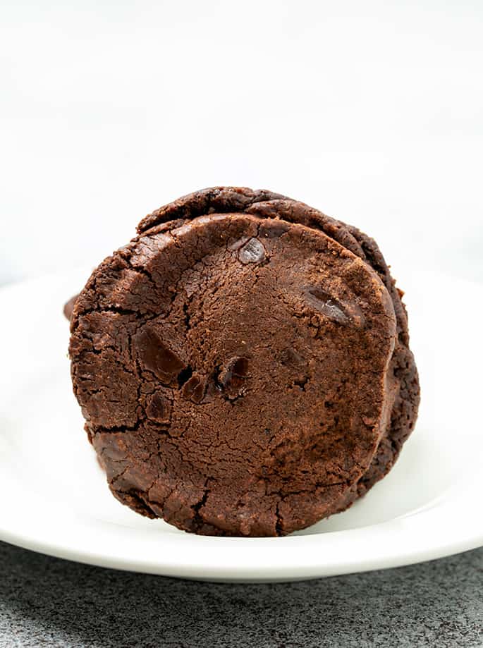 One round chocolate chip cookie standing up on small white plate