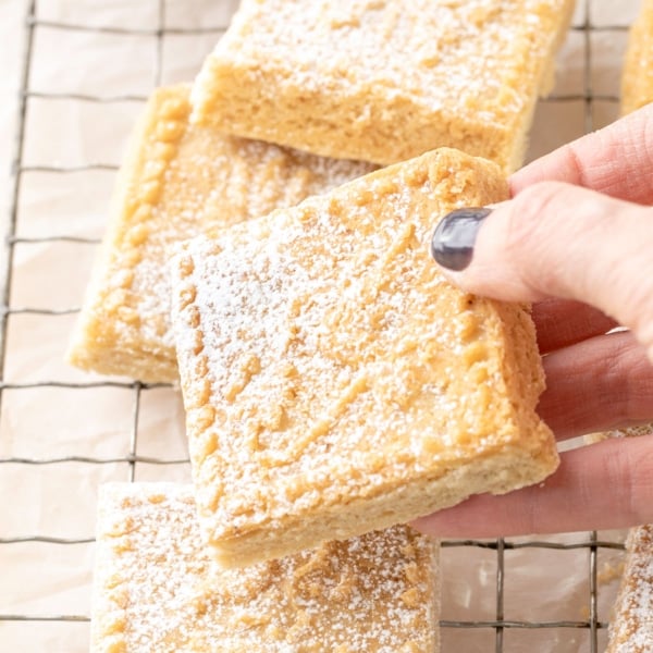 Hand holding British gluten free shortbread square over wire rack